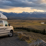 Wohnmobil an einem Aussichtspunkt mit Blick auf ein weites Tal, einen Fluss und Berge bei Sonnenuntergang