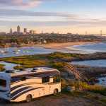 Wohnmobil an einer Küste mit Leuchtturm, Segelbooten und Stadtblick bei Sonnenuntergang